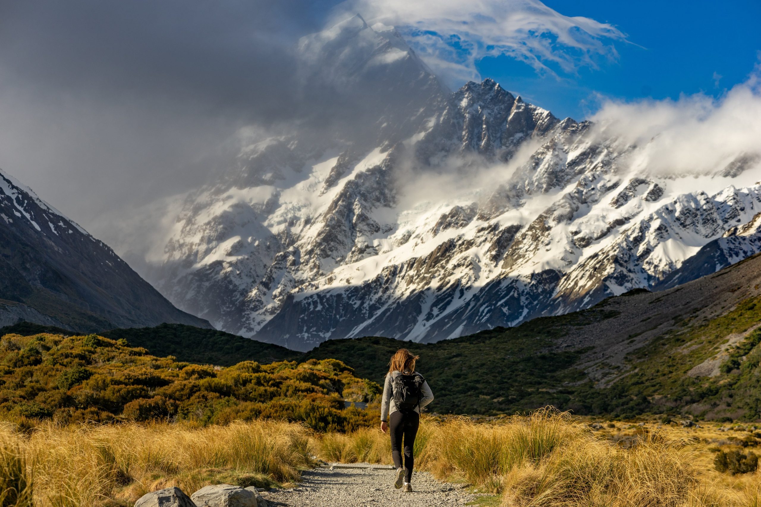 Hiker Approaches Snow Capped Mountains